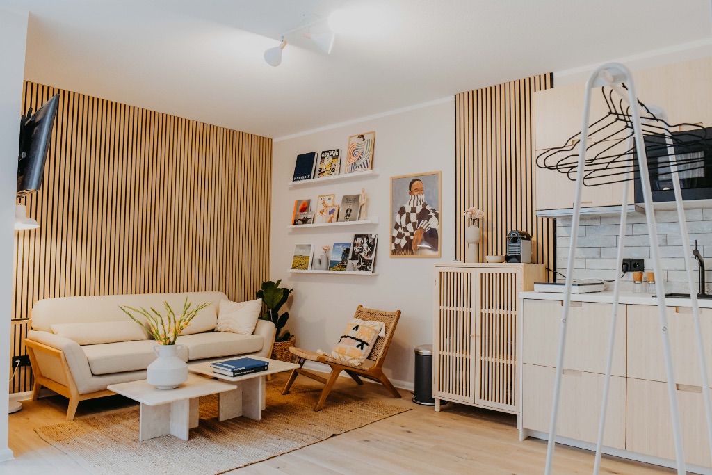 sleepArt hygge · living room with sofa, wooden slat wall and bookshelves